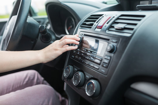 woman turning button of radio in car