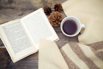 A cup of hot tea and a book on a wooden background. Flat lay