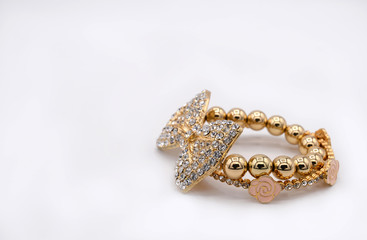 Beautiful set of gold bracelets on white background. Pink flora and diamond ribbon bracelet