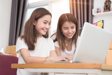 Two young Asian girl teamwork in freelance do small business with laptop to check order, online shopping and marketing. Packaging business and Small business concept