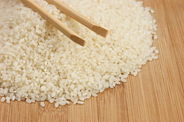 raw rice and chopsticks on bamboo board