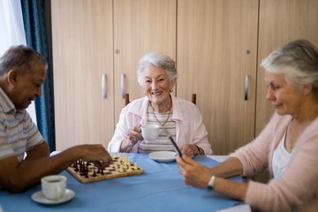 Smiling woman having coffee while sitting with friends