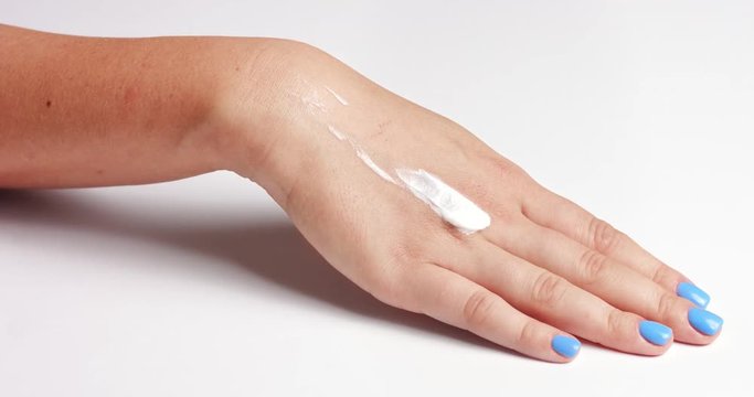 Clean well manicured hands of a young woman, applying hand cream, skin care on white background close up