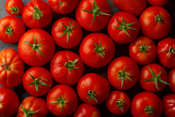 Fresh juicy raw organic tomatoes on a dark background. Selective focus. Top view. Copy space.