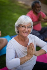 High angle view of smiling senior woman meditating in prayer