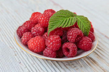 Raspberries in a bowl on a wooden white table
