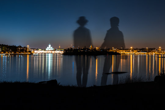 Couple standing holding hands looking at the scenery at night at Suomenlinna island in Helsinki Finland