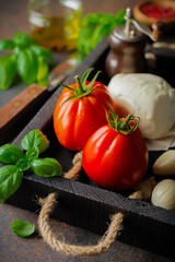 Ingredients for making traditional italian salad caprese in  wooden box on dark slate or rusty metal background.  Selective focus.  Copy space.