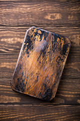 Rustic white chopping board on old brown wooden grunge plank background. Copy space.