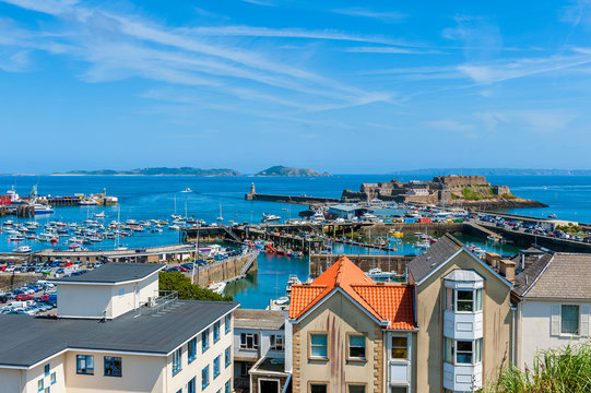 High angle view over Harbor of Saint Peter Port, Guernsey, Channel Islands, UK. The Islands of Herm and Sark are visible in the distance