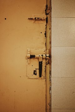 Close up view of yellow metallic door with bolt lock in old prison.