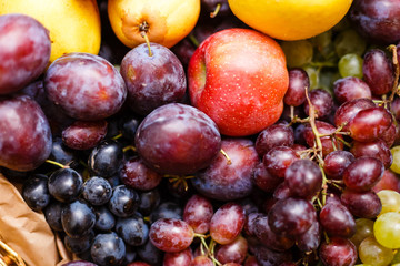 Apples plums and grape on a wooden background freshly washed on a plate