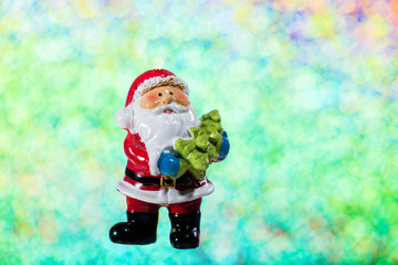 Ceramic figure of Santa Claus. Christmas decoration on multi color glitter blur background. 
