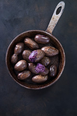 Raw potato food . Fresh blue potatoes on dark background. Free place for text.