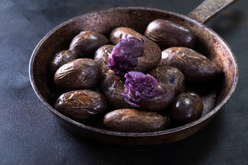 Raw potato food . Fresh blue potatoes on dark background. Free place for text.
