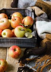 Ripe apples in box with plaid on wooden background. Top view. Selective focus