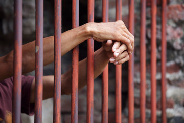 hands of prisoner in jail as background.