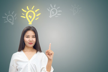 portrait of beautiful Asian business woman standing finger point at copy space over grey wall background with doodle light lamp icons 