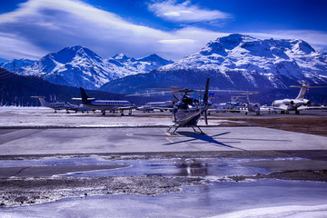 Fototapeta premium Private jets and a helicopter in the airport of St Moritz Switzerland