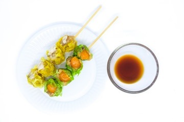 Close up yellow crab-filled & green salted egg pork-filled chinese steamed dumpling or dim sum serve with sour sauce (jigsaw) on white dish, isolated on white background - food chinese concept.