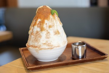 Two tone kakigori (Japanese shaved ice dessert flavor with chocolate powder) serve on white bowl with chocolate sauce.