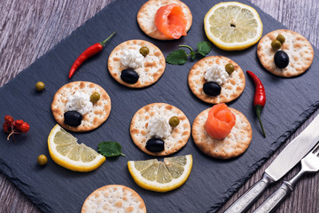 Crackers with red fish and olives on a stone plate. Selective focus