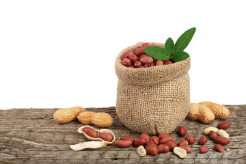 peanuts with leaf in bag on old wooden background