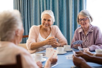 Smiling senior female friends playing cards