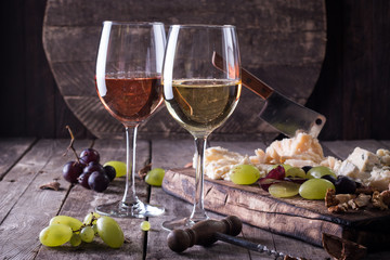 Different kinds of cheeses, wine, fruits and snacks on rustic wooden table . still life concept