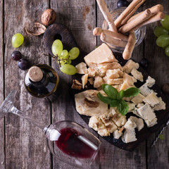 Different kinds of cheeses, wine, fruits and snacks on rustic wooden table . still life concept