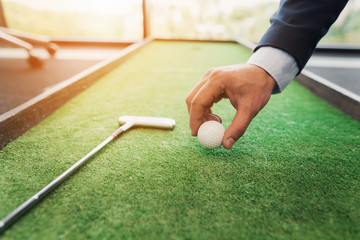 Close up. A man in a business suit plays golf in the office