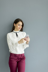 Elegant businesswoman with mobile phone by the wall