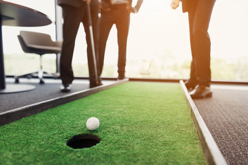 Close up. Men play in an office in a mini golf. One of them holds a golf club in his hands