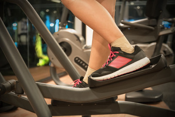Closeup cardio workout of young people working out on an elliptical trainer in gym
