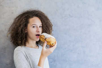 Cure curly hair girl eating croissant