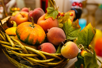 Fototapeta na wymiar Basket with peaches and pears ripe yellow pumpkin among autumn leaves on a windowsill