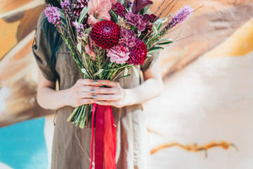 Woman hand holding bouquet of fresh flowers on light
