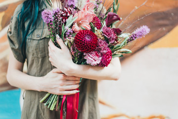 A woman holding a bunch of colourful flowers in outstretched hands