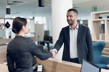 A young man in a business suit came to the office. He greets the woman secretary