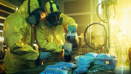 In the Underground Drug Laboratory Two Clandestine Chemists Mix Chemicals while Cooking Narcotics. They Use Canisters and Beakers, Toxic Compounds Create Smoke. They Work in the Abandoned Building.