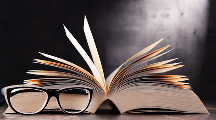 Composition with open book and glasses on the table