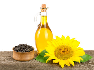 Sunflower oil, seeds and flower on wooden table with white background