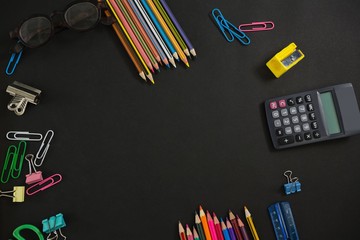 Various school supplies and apple arranged on black background