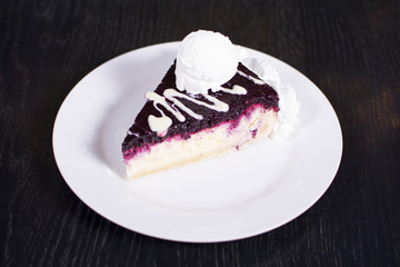 Blueberry cheesecake on a ceramic white plate with ice cream. Delicious dessert in a restaurant.