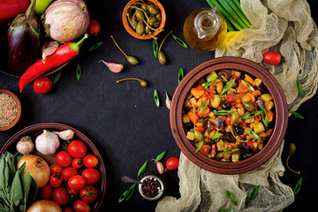 Hot spicy stew (caponata) eggplant, zucchini, sweet pepper, tomato, carrot, onion, olives and capers. Flat lay. Top view