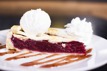 Delicious homemade cherry pie with a flaky crust top view. Ice cream balls on a plate.
