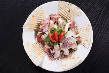 Salad with prosciutto and cheese on white plate close up. Served restaurant table. Delicious meal at a luxury restaurant.