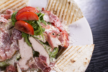 Salad with prosciutto and cheese on white plate close up. Served restaurant table. Delicious meal at a luxury restaurant.
