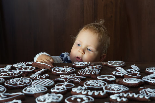 Small boy tries to grab traditional homemade Christmas ginger and chocolate cookie decorated with white sugar painting