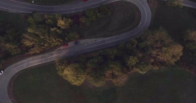 Aerial view of asphalt contryside roadsurrounded by forest. Car drives in the country at sunset, top view. Transportation, lifestyle concept.